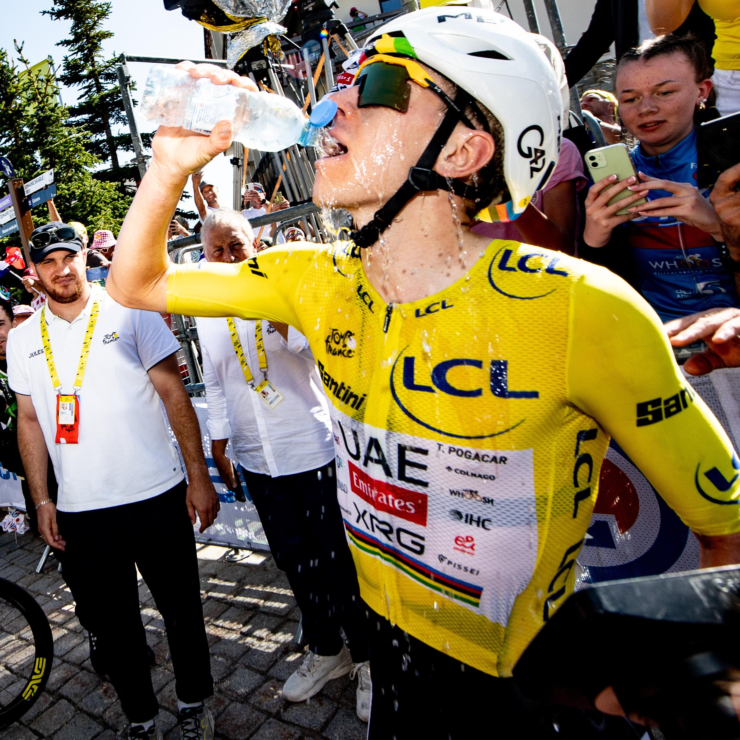 Tadej Pogacar drinks water as he celebrates after crossing the finish line to win stage 19.
