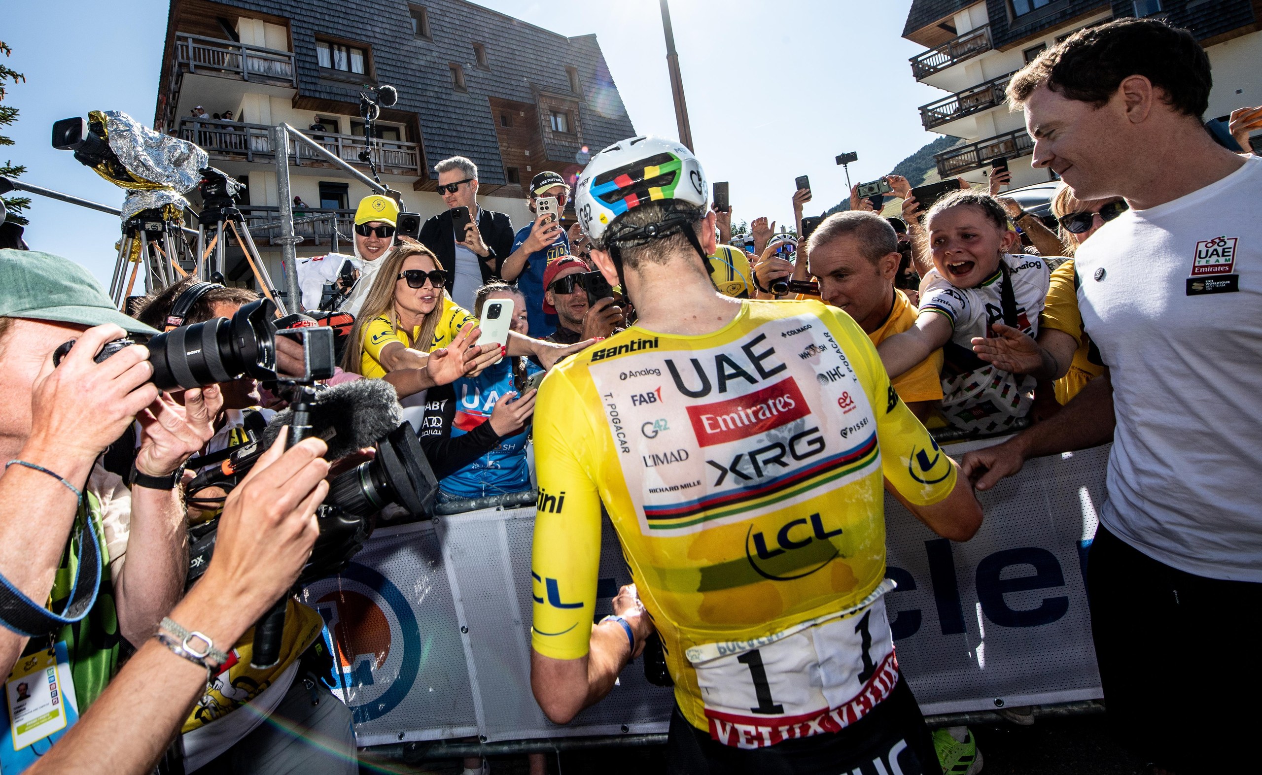Tadej Pogacar celebrates with fans after crossing the finish line to win stage 19.