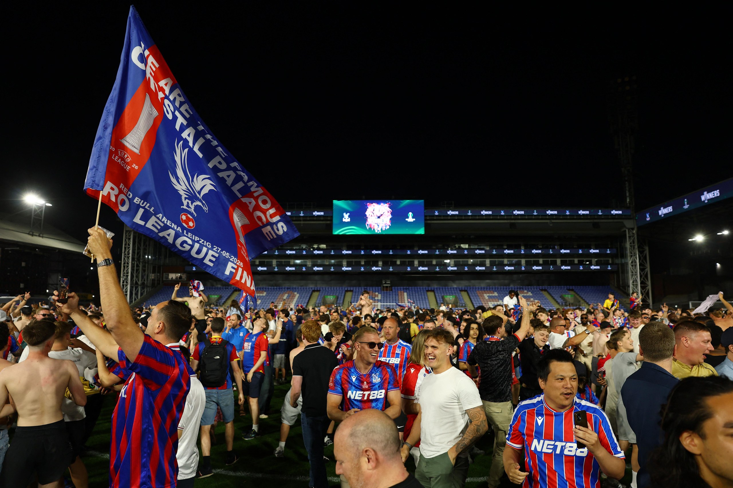 Crystal Palace fans celebrate on the Selhurst pitch after winning the UEFA Conference League final.