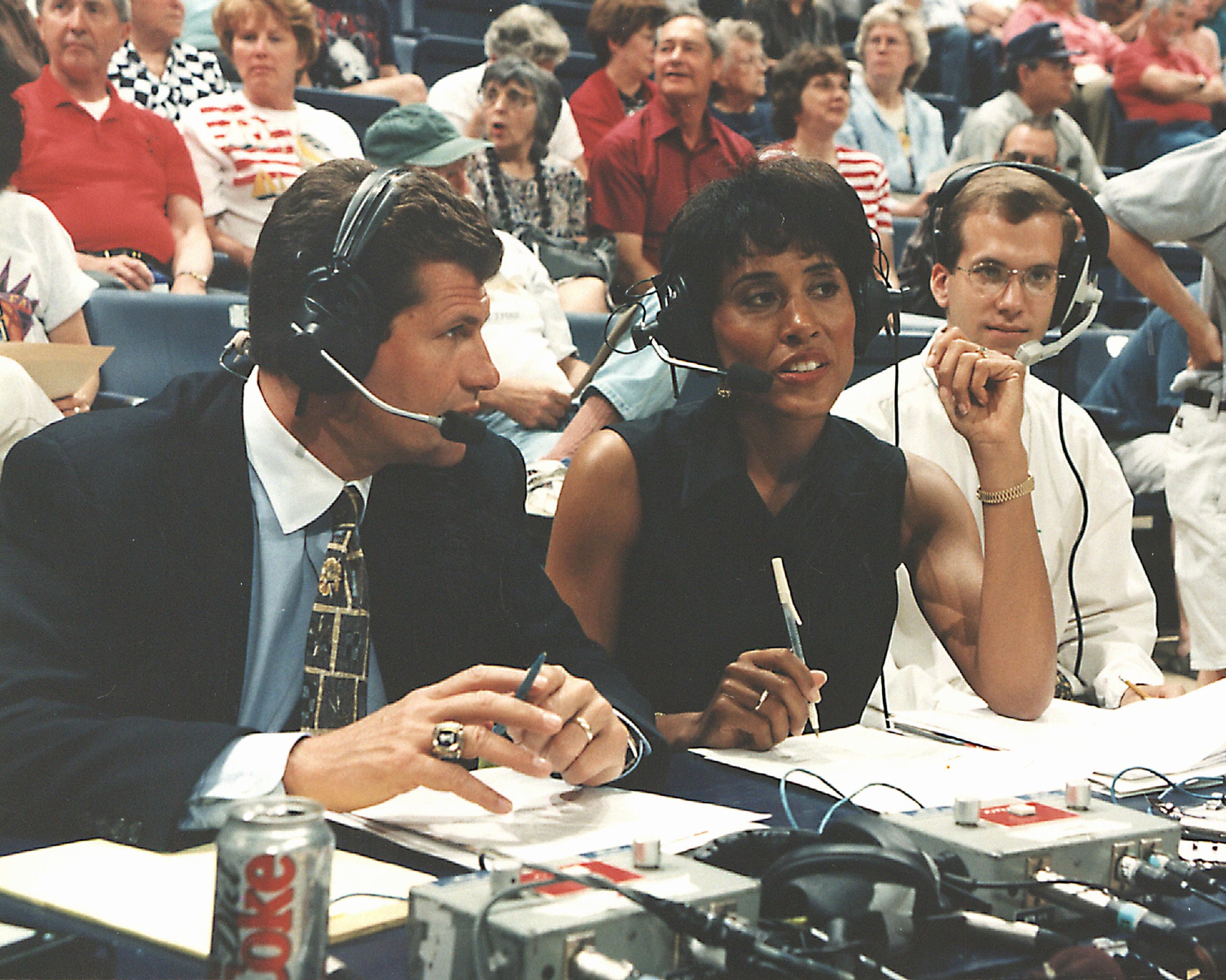 Geno Auriemma and Robin Roberts wear headsets while broadcasting a basketball game.