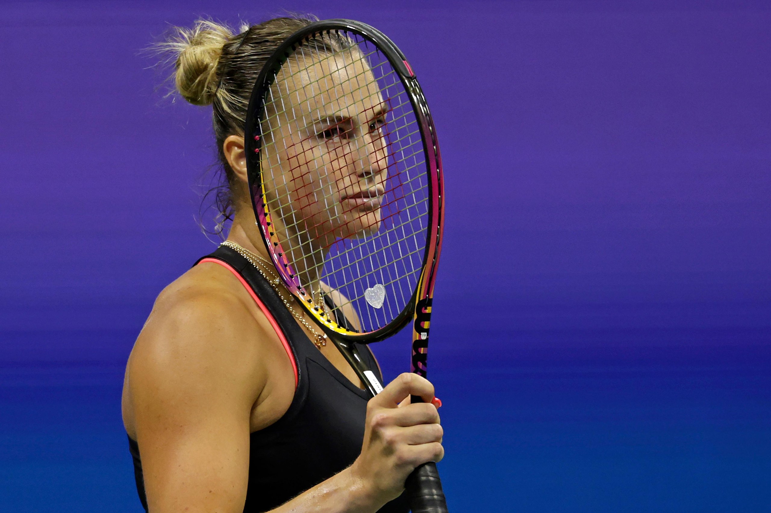 Aryna Sabalenka looks dejected behind her racket on court