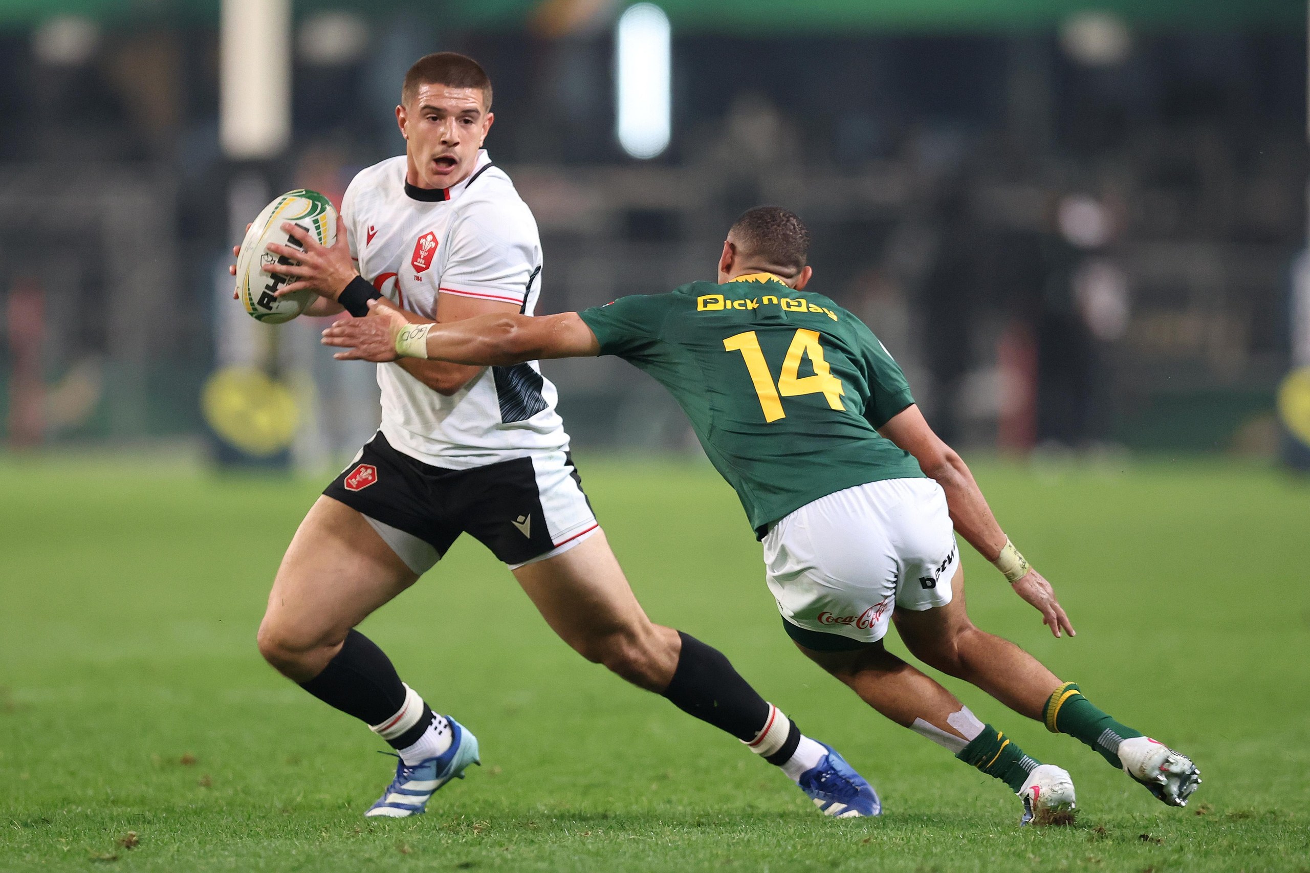 Joe Hawkins of Wales runs with the ball under pressure from Jaco Williams.