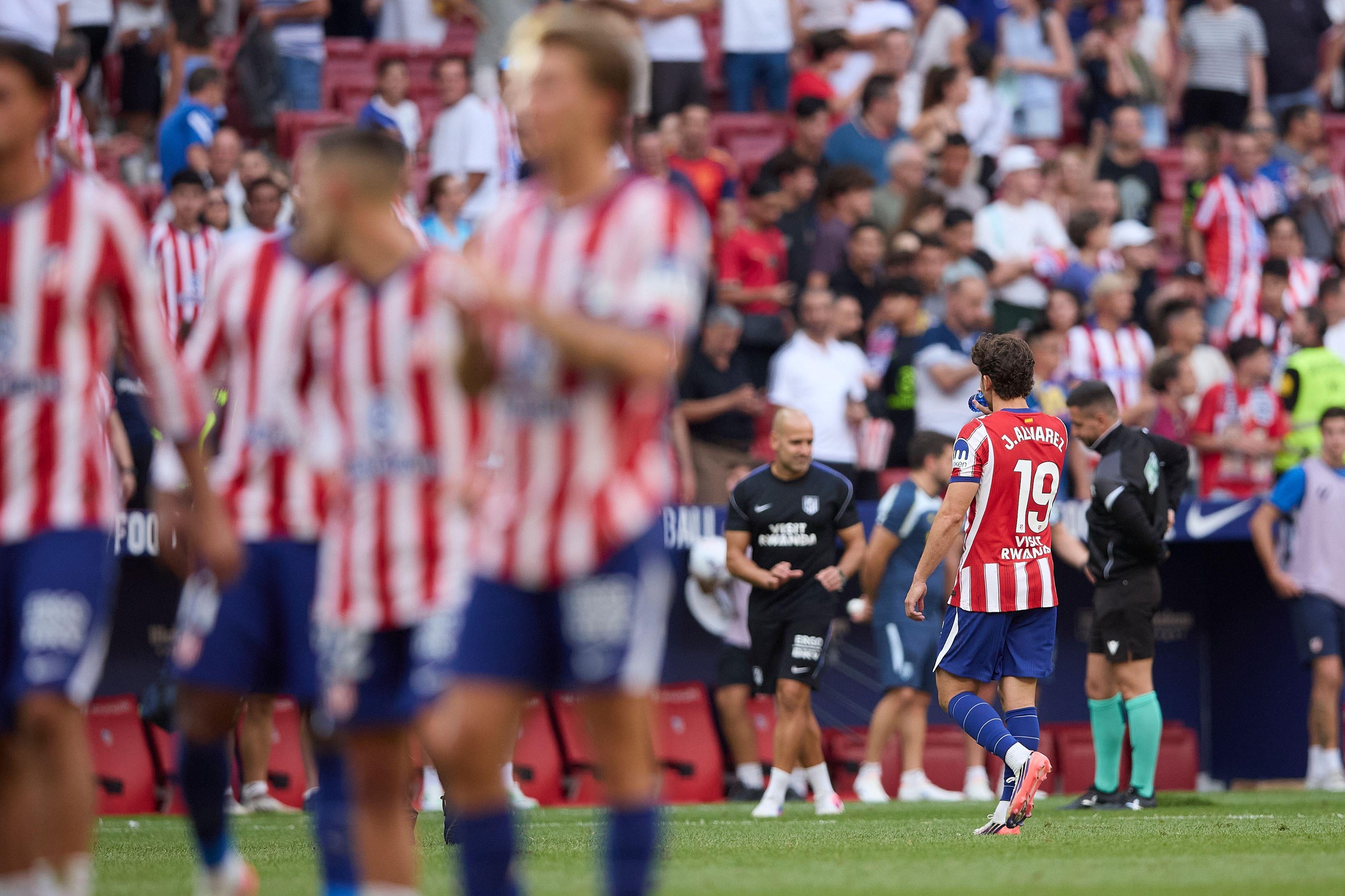 Julián Álvarez trudges off the pitch alone as his Atlético Madrid teammates applaud the fans.