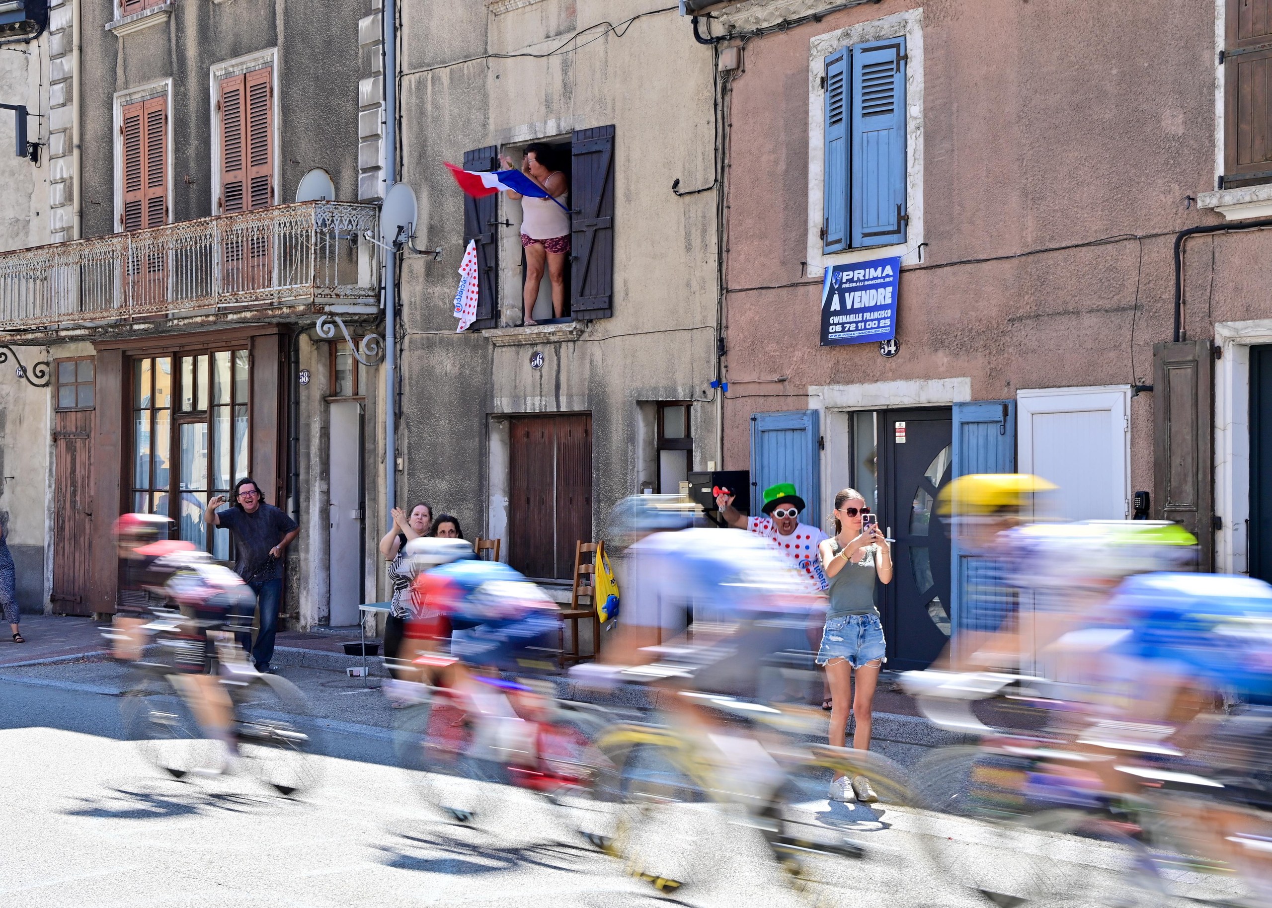 Spectators take pictures as the riders pass through their town on stage 18 between Voiron and Orcieres-Merlette