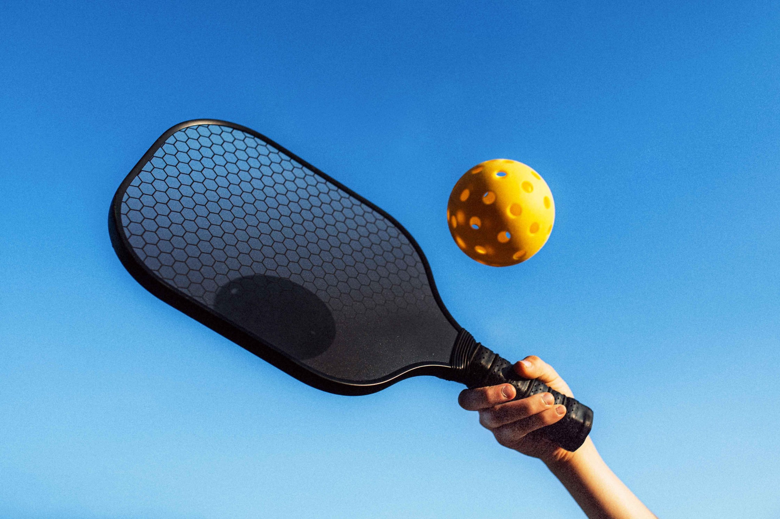 a person hitting a pickleball with a paddle