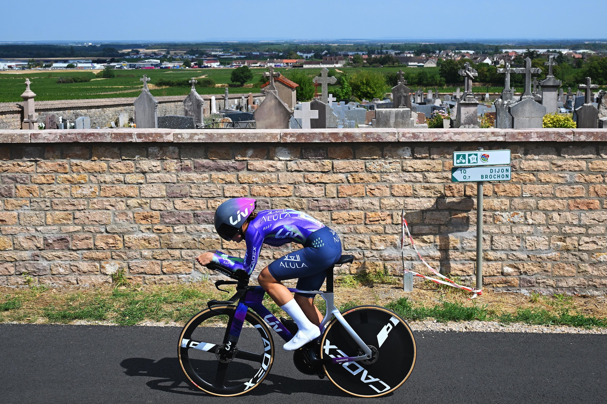 Mackenzie Coupland of Liv AlUla Jayco passes a cemetery on her way to Dijon.