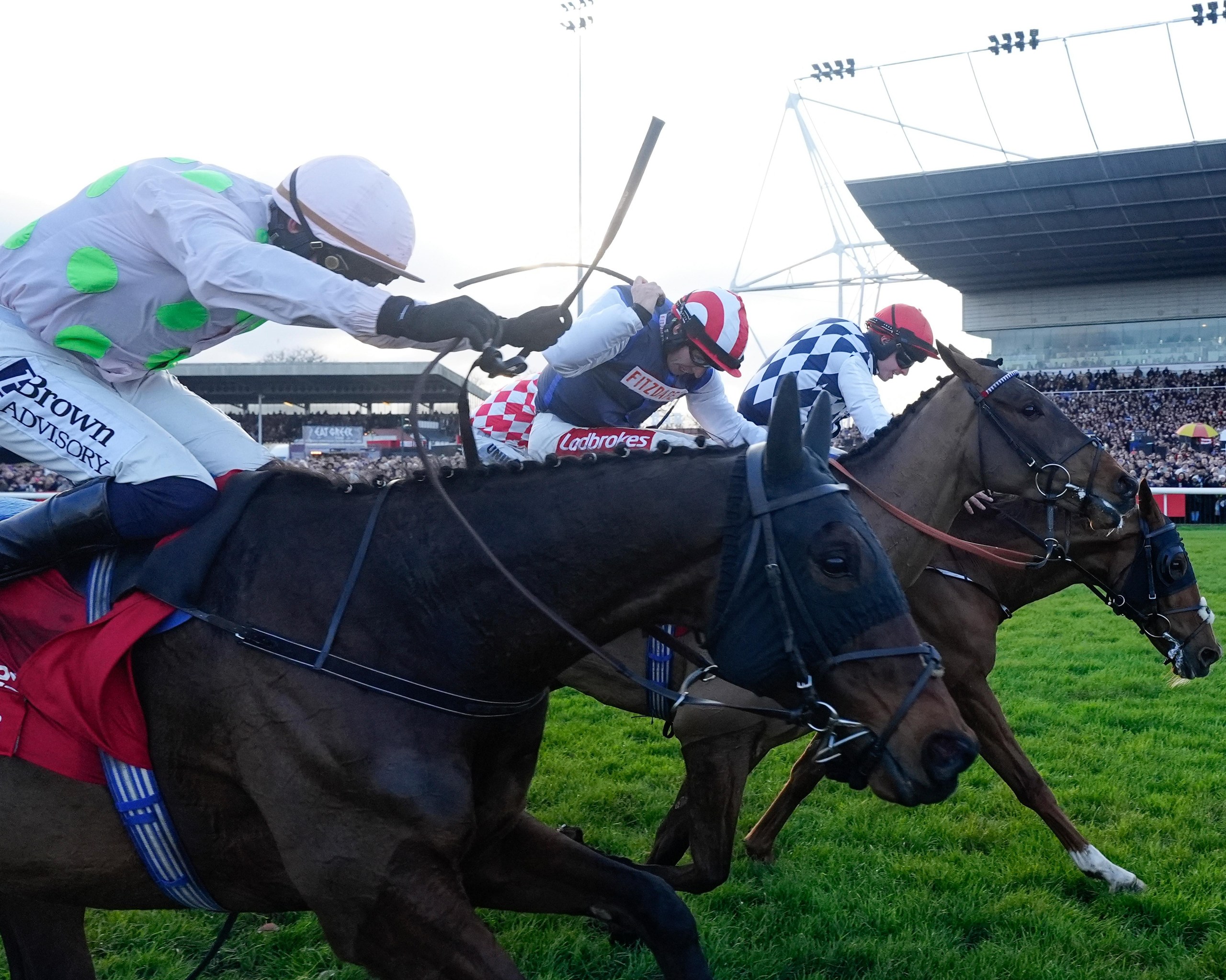 A side view of three horses running the King George VI Chase at Kempton Park, which Ben Jones (centre) on The Jukebox Man won.