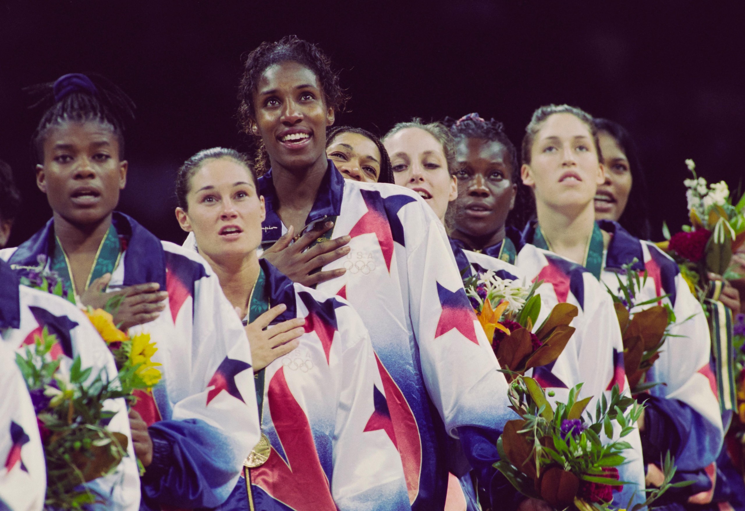 Sheryl Swoopes, Jennifer Azzi, Lisa Leslie, Carla McGhee, Katy Steding, Katrina McClain, Rebecca Lobo and Venus Lacey (left to right) look on from the podium.