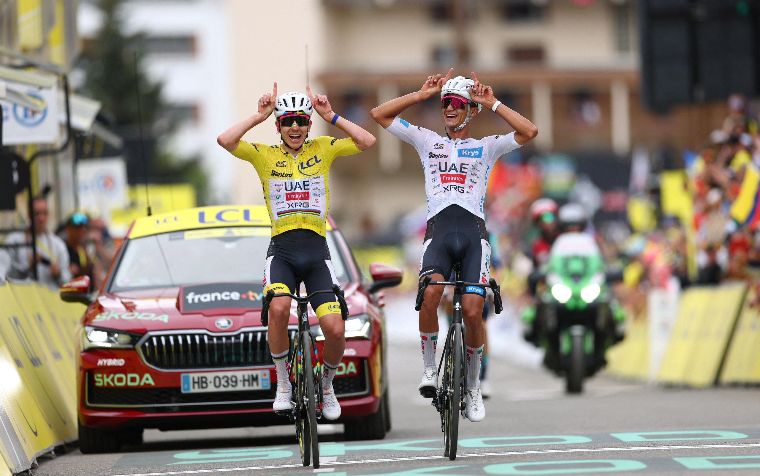 UAE Team Emirates teammates Tadej Pogacar, wearing the yellow jersey, and Isaac Del Toro, wearing the white jersey, celebrate after crossing the line to finish stage 20.