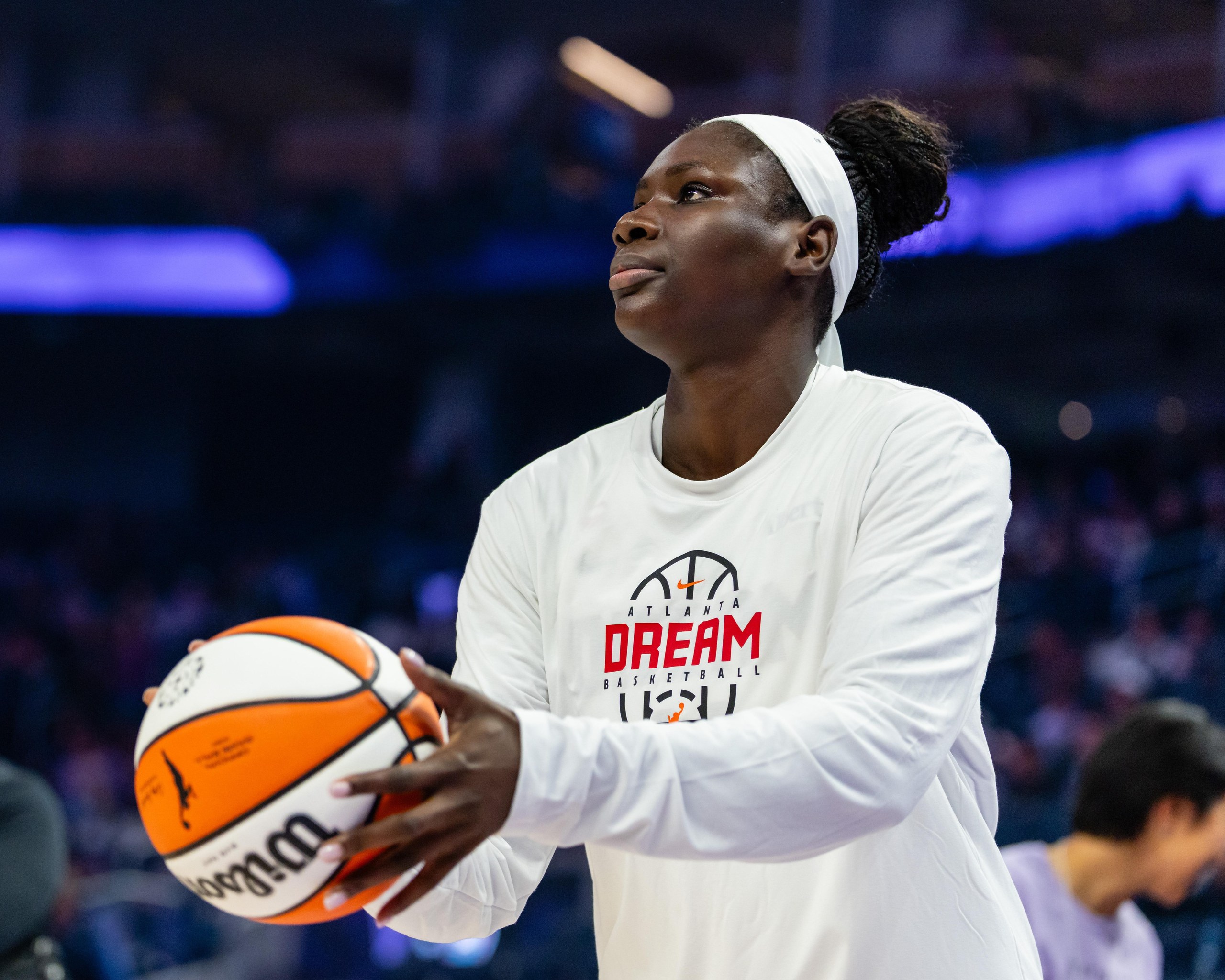Woman in white holds orange and white basketball