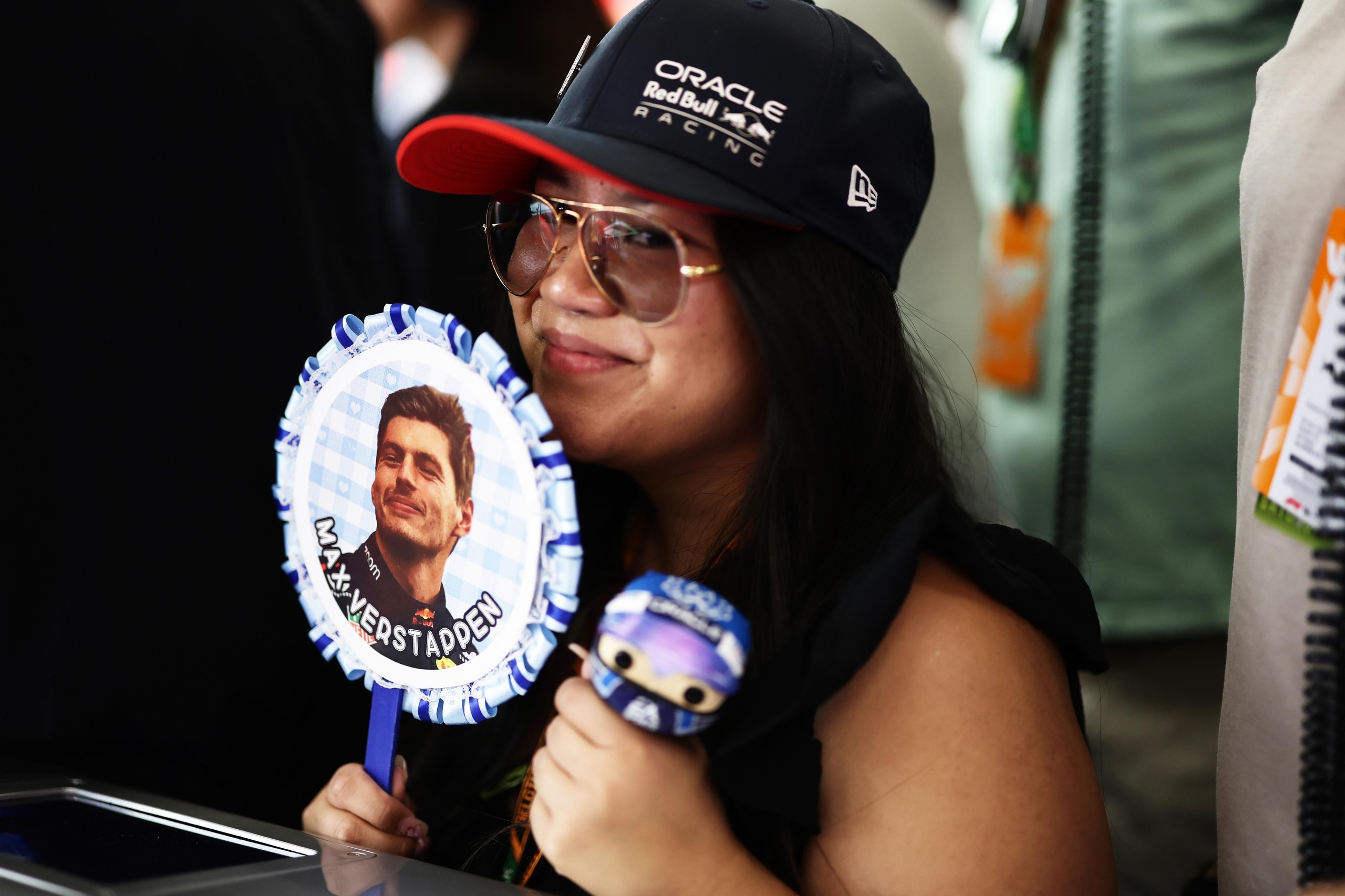 A woman holding a Max Verstappen fan.
