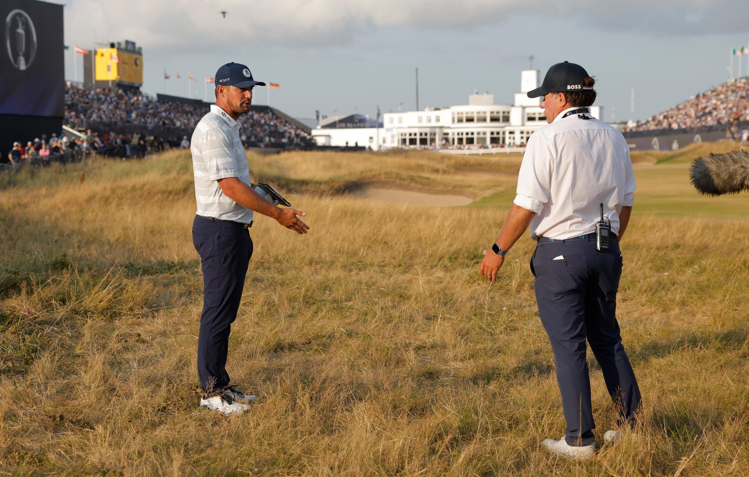 Bryson DeChambeau talks to an R&A rules official on the 18th hole of his third round