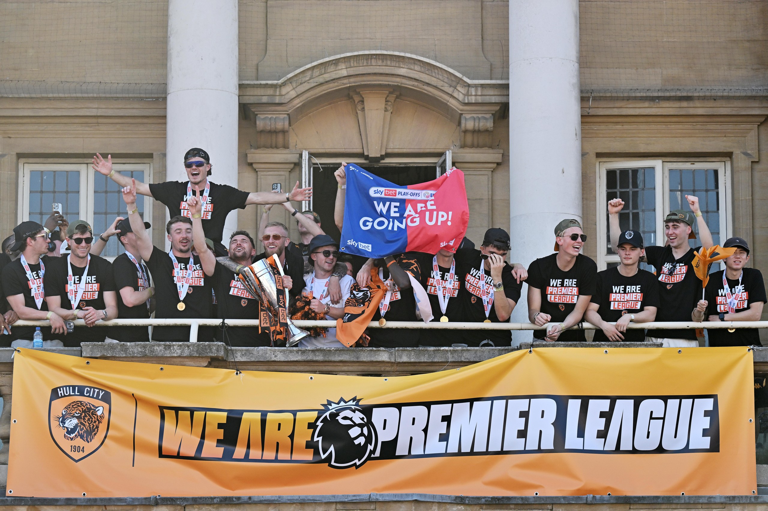 Hull City players celebrate reaching the Premier League on a balcony at a civiv building
