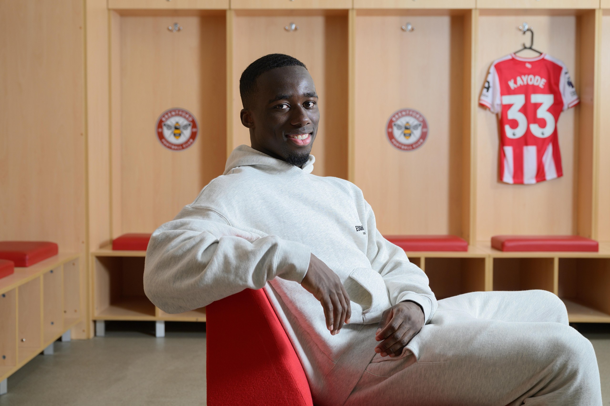 Michael Kayode poses with a Brentford shirt in the background.